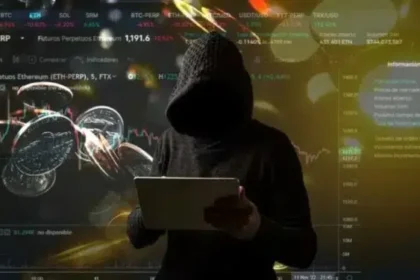 Usuario desconocido con gabardina negra utilizando una laptop.