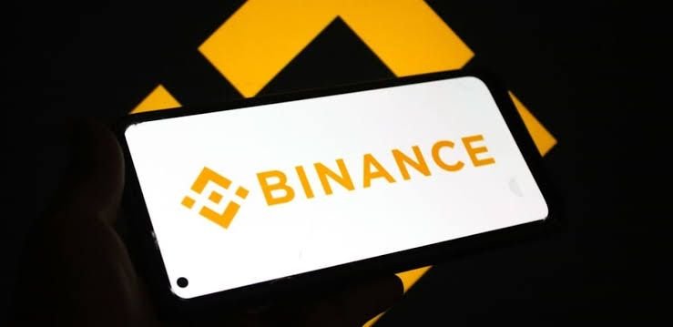 Logo de Binance atrás con el logo de Binance en un teléfono inteligente